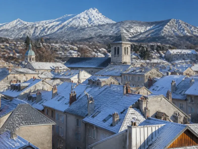 Toits de Gap et sommets enneigés en arrière-plan sous un ciel d’hiver