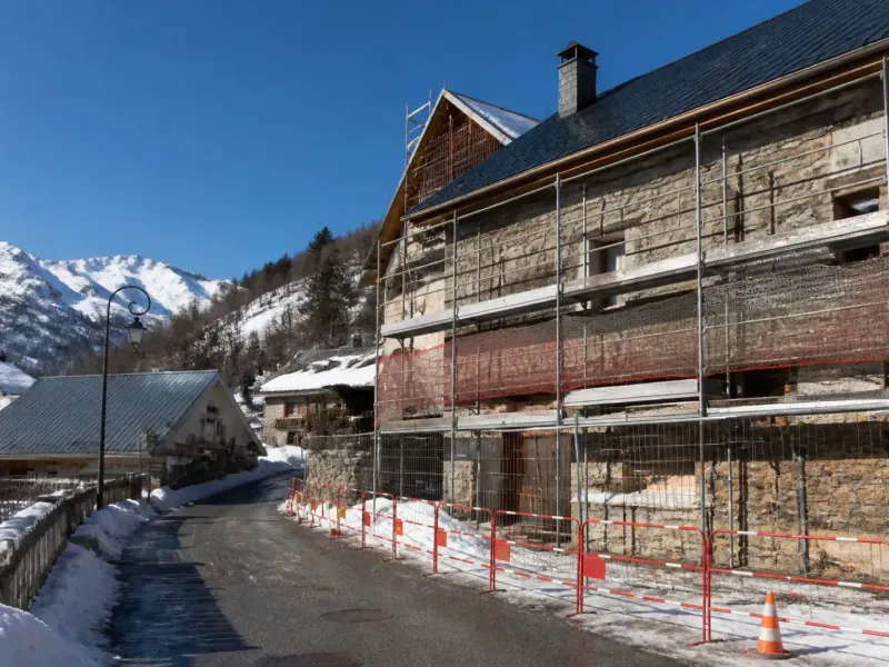Chantier de rénovation en hiver dans une rue de montagne, accès dégagé et sécurisé